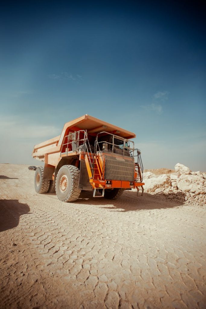 Massive dump truck on a dusty road in Texas City desert, clear sky above.