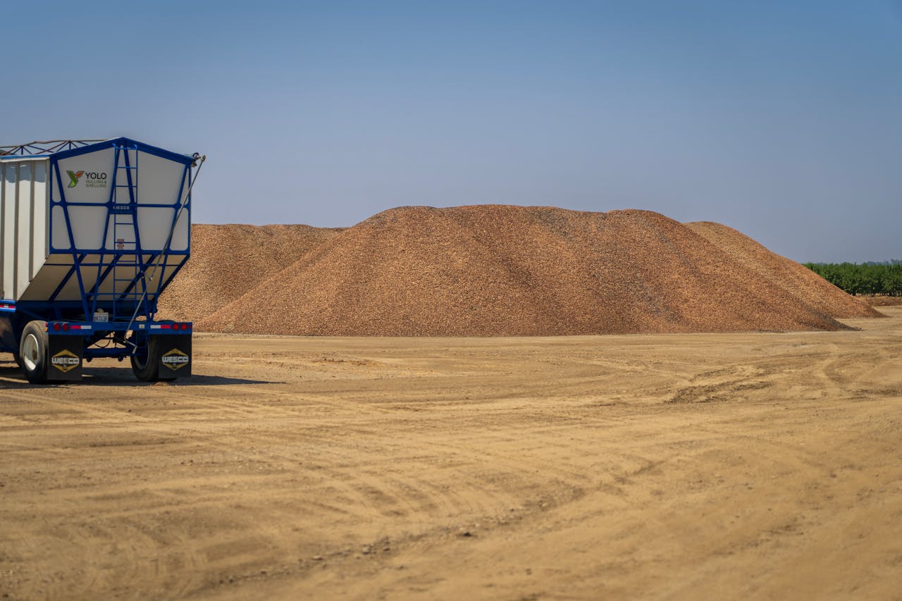 A barren landscape featuring sand piles and a transportation truck under a clear sky.